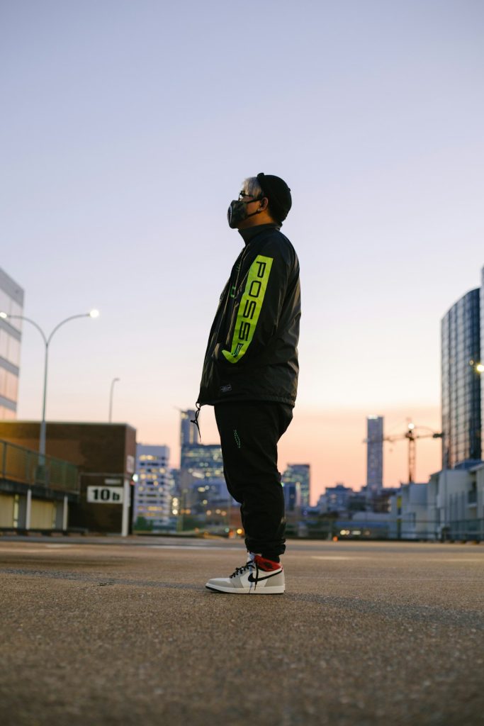 man-in-black-and-green-jacket-and-black-pants-wearing-black-helmet-walking-on-gray-concrete-zgovdmctsco