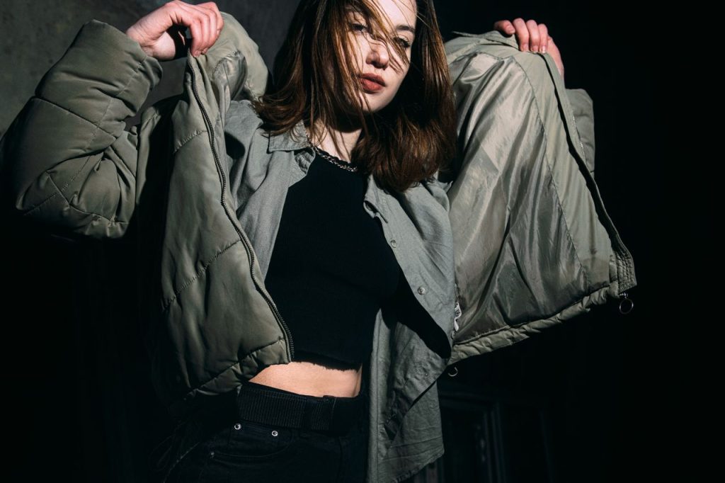 Young woman adjusting her winter jacket in a fashion studio setting.