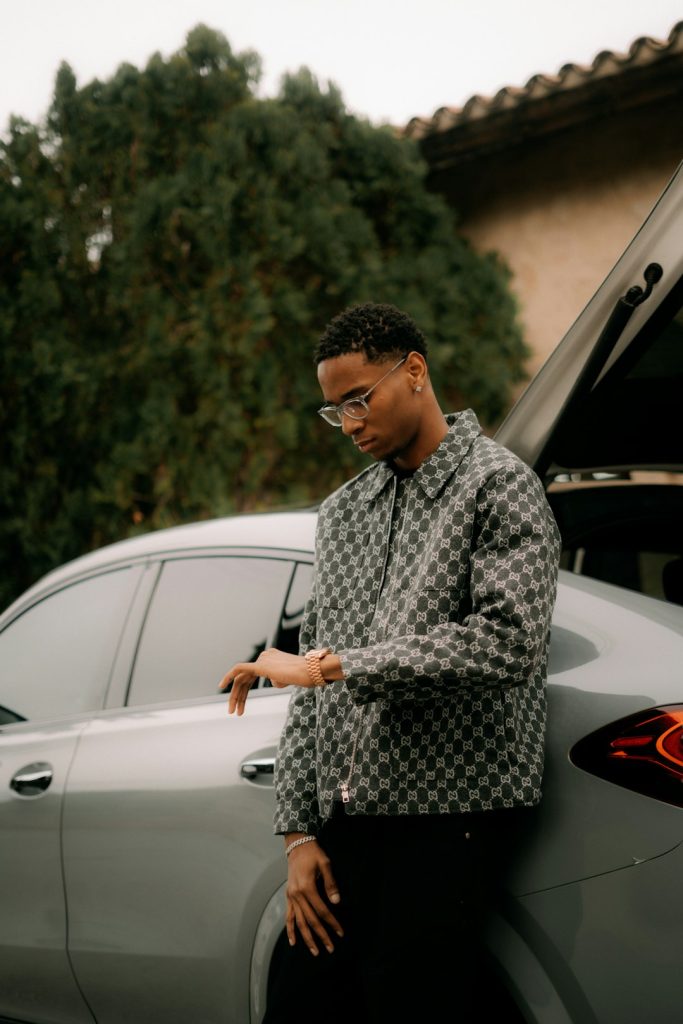young-man-in-checkered-jacket-leaning-on-car-puqraxhmwnu